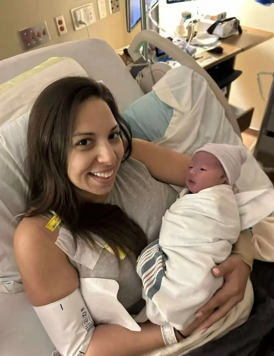 A surrogate holding a newborn with support in the hospital
