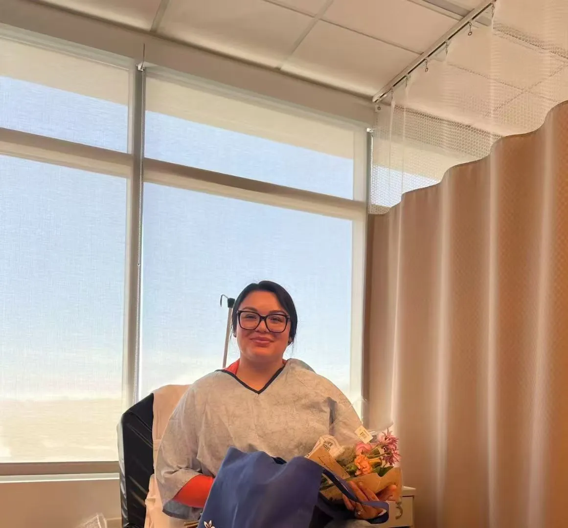 A surrogate smiling after delivery during hospital recovery